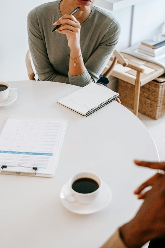 Buy-to-Let Secured Loans | Woman sitting at a white round table discussing mortgage options